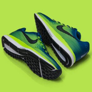 From above of colored sneakers with blue and green surface and green and white and black sole for comfortable moving around streets against green background