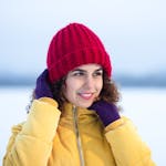 Young woman enjoying a winter day, wearing a bright red hat and yellow jacket.
