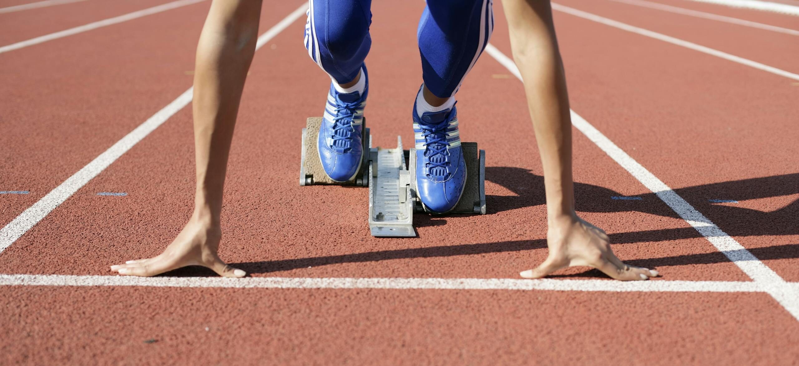 Close-up of an athlete starting a race at the track field on a sunny day.