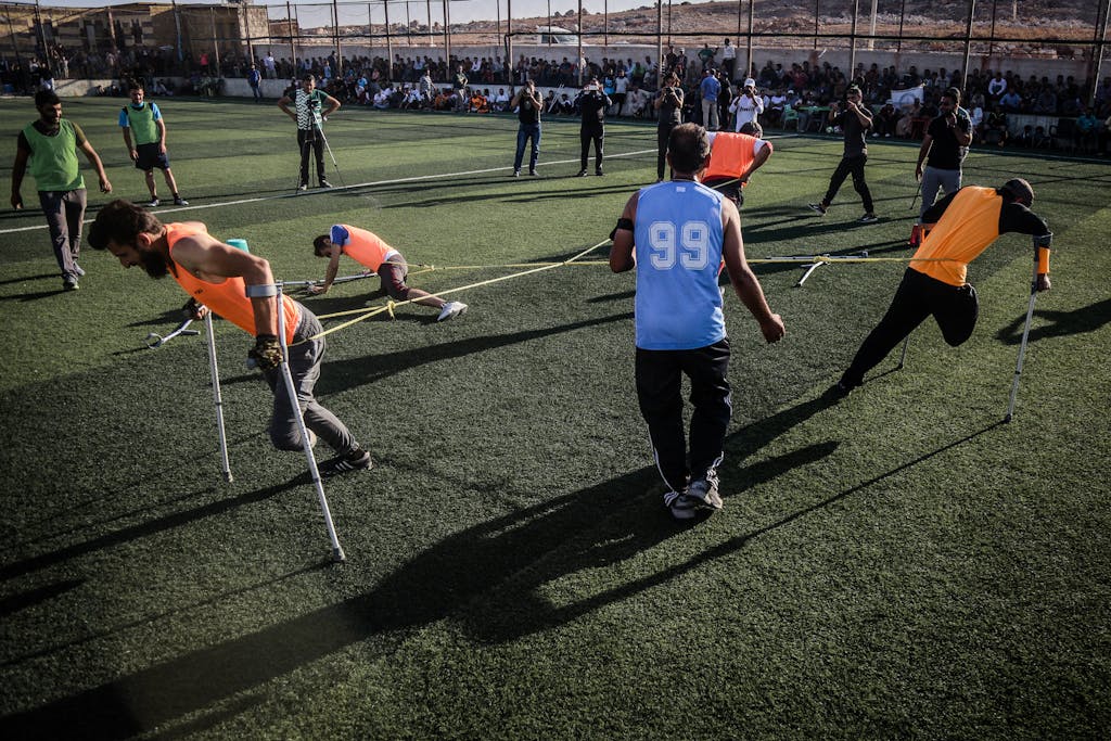 Disabled athletes competing in a team sport on a grassy field in Syria.