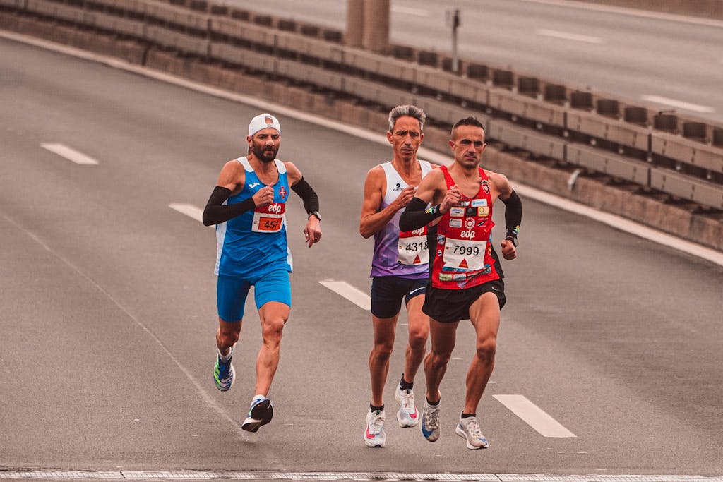 Three male marathon runners on a city street showcasing endurance and competition.