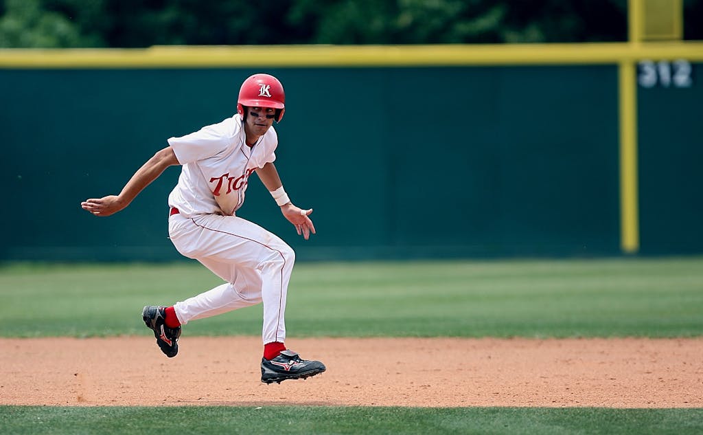 Athlete in action running on baseball field, wearing helmet and uniform.
