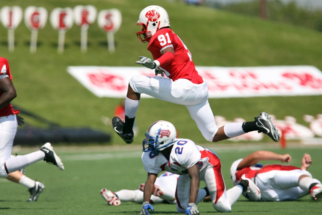 High-energy American football action with players in motion on the field during a daytime match.
